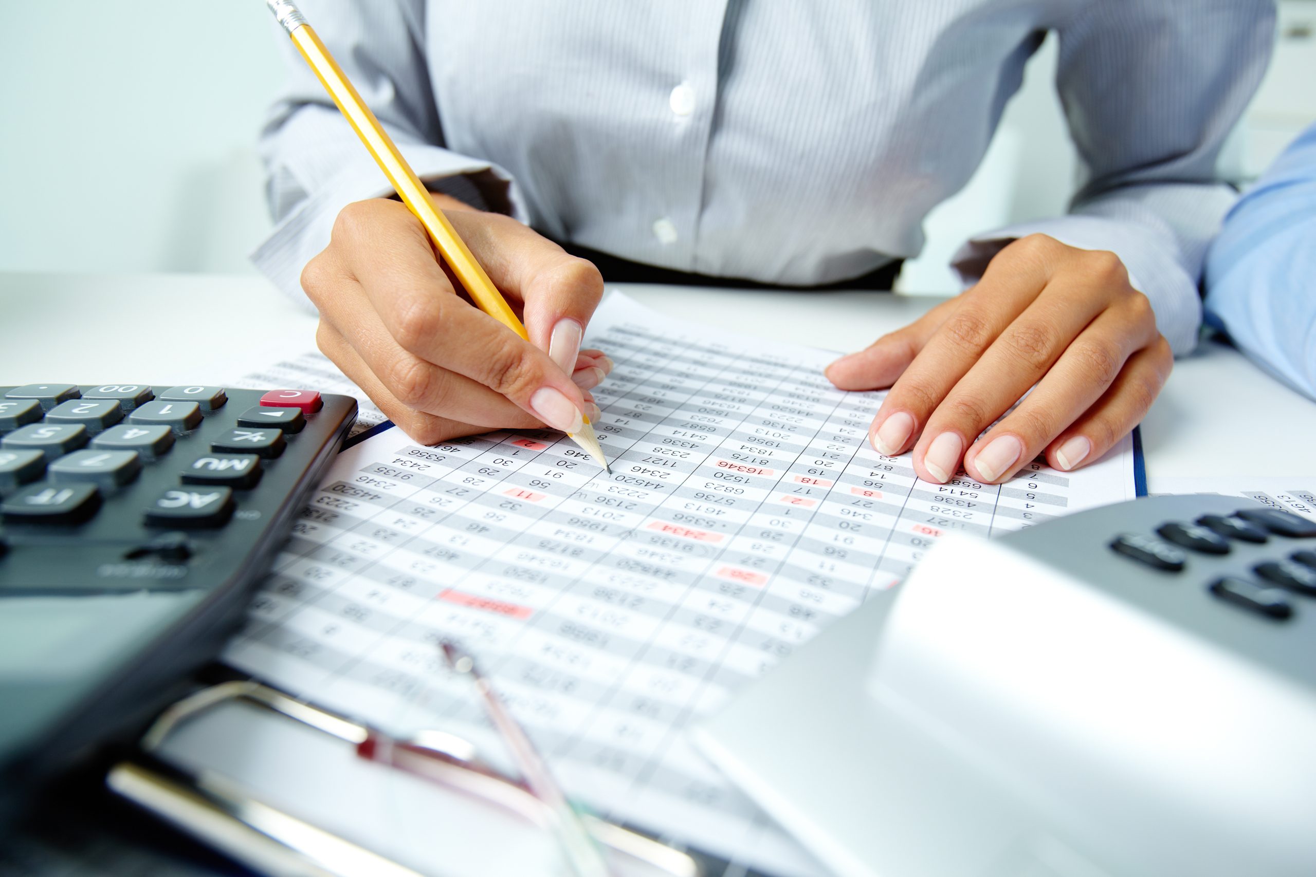 Photo of human hands holding pencil and ticking data in documents